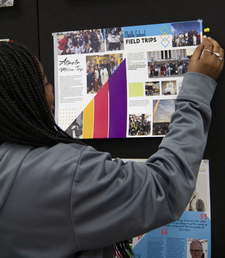 A girl with her back to the camera putting up a mock spread on the wall.