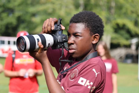 Yearbook photography student at a sporting event with camera